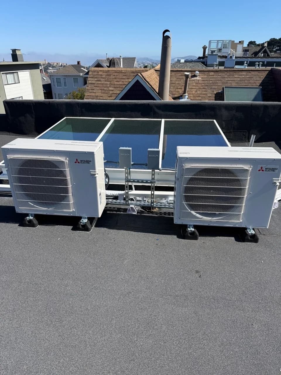 Three ductless mini-split outdoor units racked together on a roof